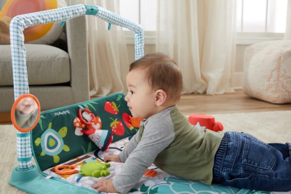 Baby speelt op kleurrijke speelmat met speelgoed.