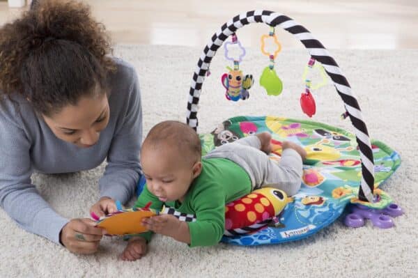 Baby speelt op speelkleed met volwassene.