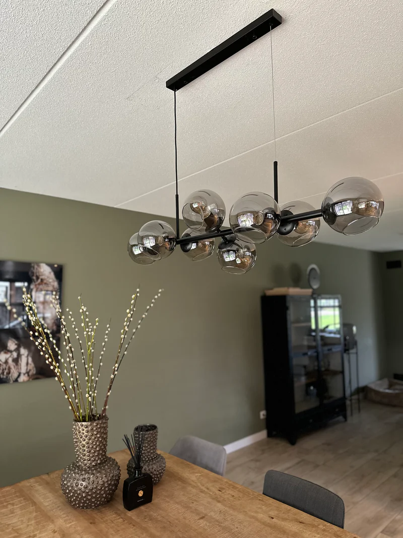 Moderne hanglamp boven houten eettafel in woonkamer.