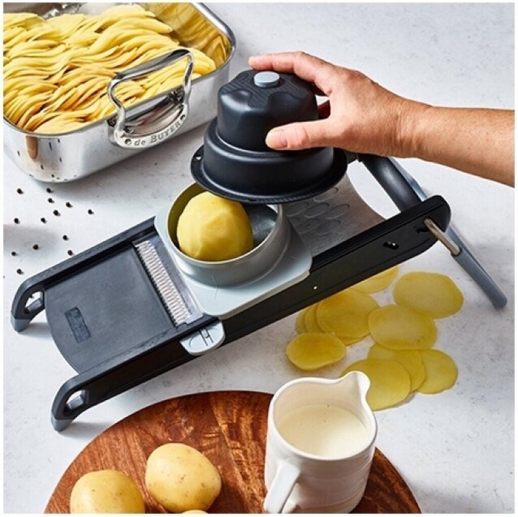 Aardappelmandoline snijdt aardappelschijfjes in keuken.