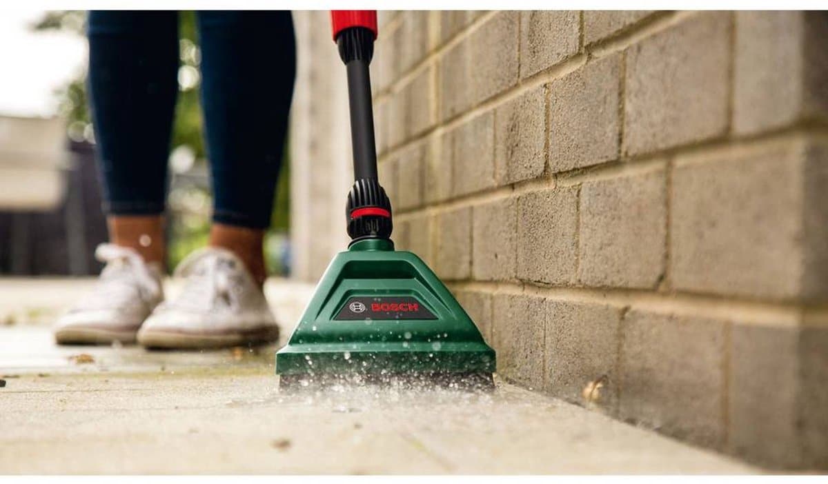Vrouw gebruikt hogedrukreiniger op stoep.
