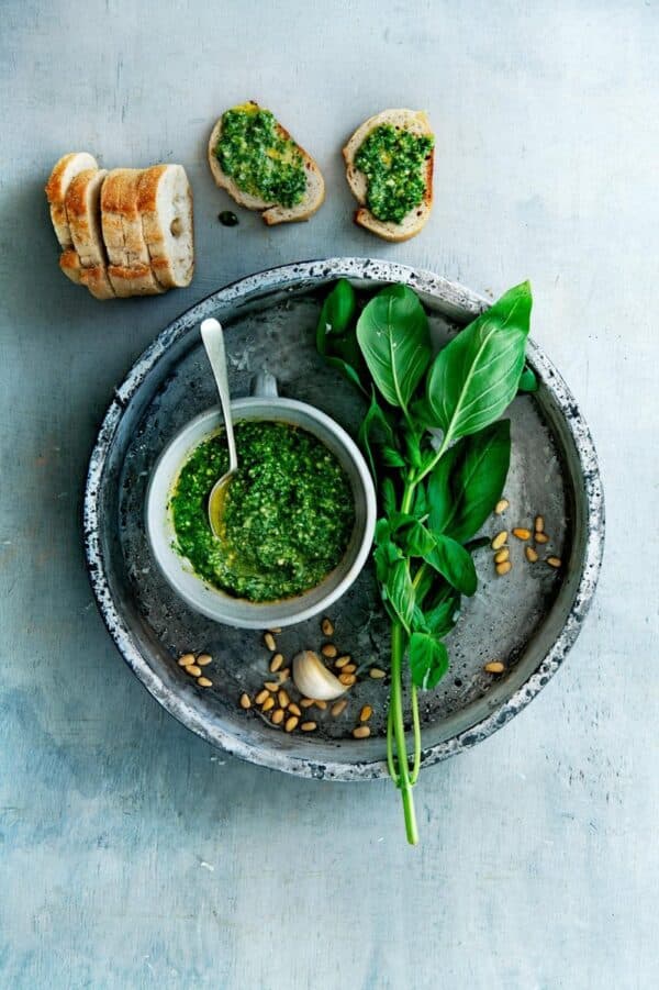 Pesto met basilicum, brood en pijnboompitten op dienblad.