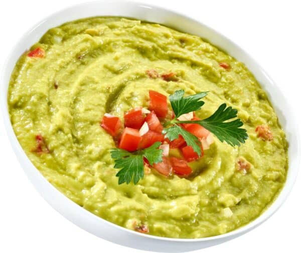 Schaal met guacamole, tomatenblokjes en peterselie.