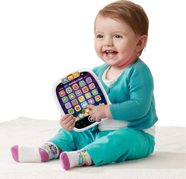 Baby speelt met educatieve tablet op kleed.