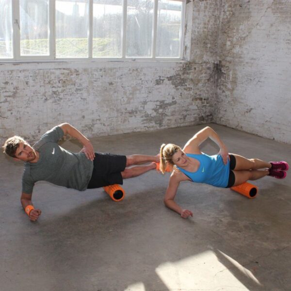 Twee mensen doen zijplankoefeningen met foamrollers.