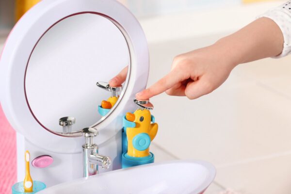 Persoon drukt op knop naast eendenspeelgoed in badkamer.