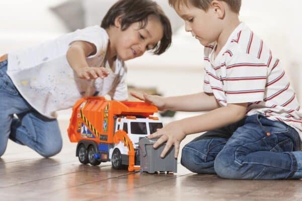 Kinderen spelen met speelgoedvrachtwagen binnen.