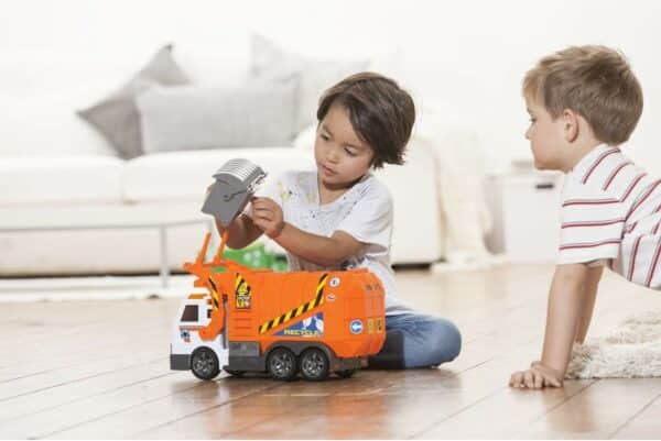 Kinderen spelen met een speelgoedvuilniswagen.