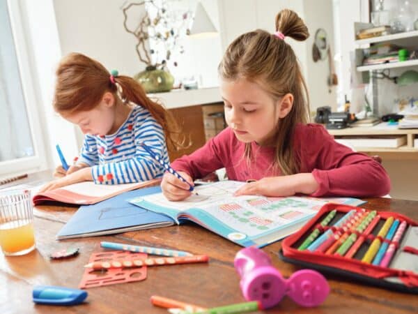 Twee kinderen bezig met huiswerk aan tafel.