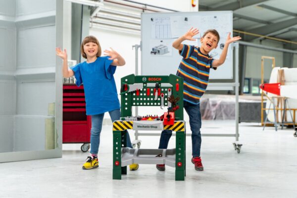 Kinderen spelend met speelgoedwerkbank in werkplaats.