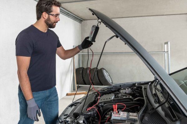 Man controleert accu auto in garage.