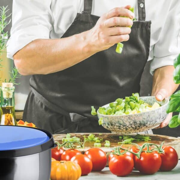 Kok bereidt groenten voor naast tomaten en kruiden.