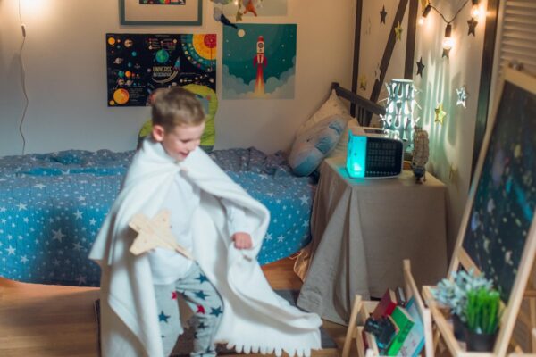 Jongen speelt astronaut in slaapkamer met sterrenhemel decor.