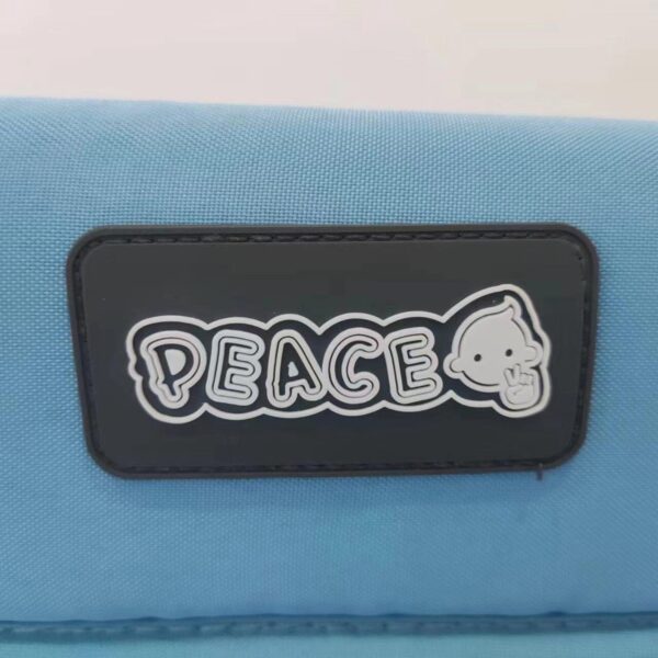 Blauwe tas met 'peace'-logo en cartoonfiguurtje.