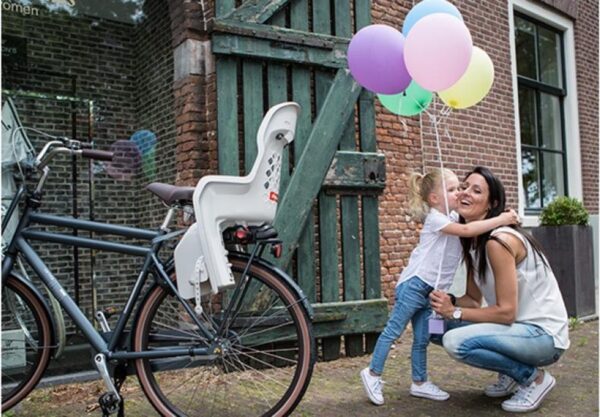 Moeder en kind met ballonnen bij fiets in tuin.