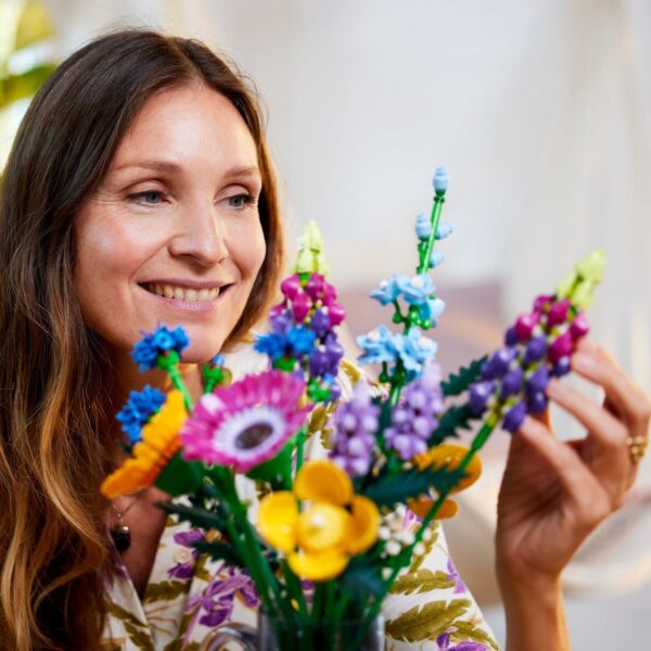 Vrouw bewondert kleurrijke LEGO bloemen.