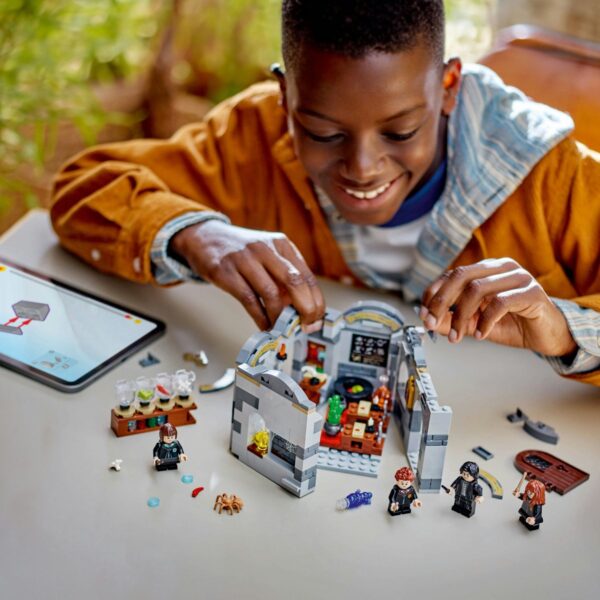 Kind speelt met LEGO en tablet op tafel.