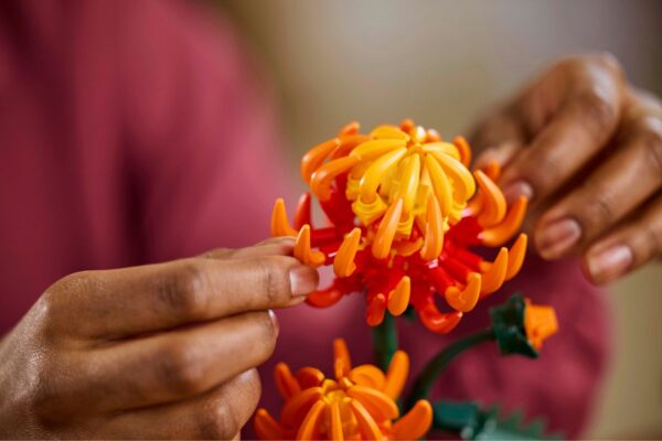 Handen bouwen kleurrijke bloemen met lego-achtige blokken.