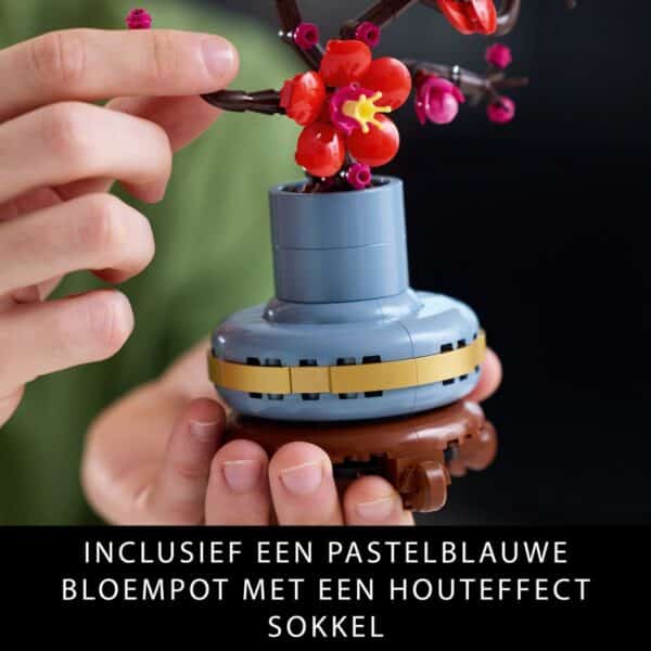 Hand bouwt kleurrijke bloemen in blauw potje.