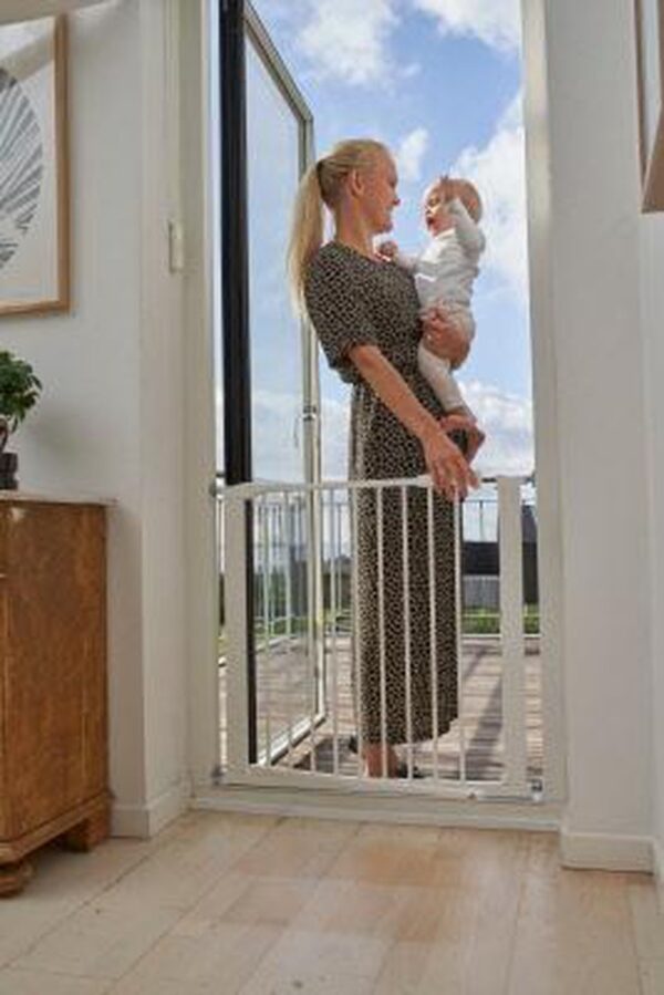 Vrouw met baby bij open balkondeur met hekje.