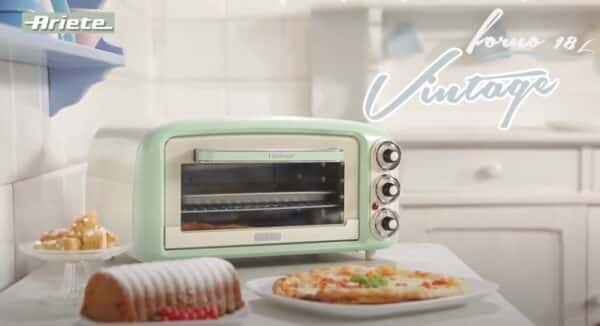 Groene vintage oven met gebak en pizza op tafel.