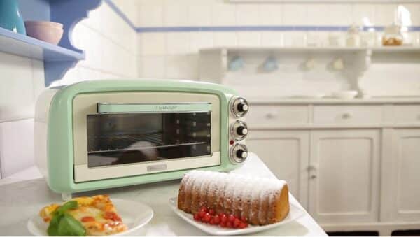 Retro groene oven met pizza en cake op aanrecht.