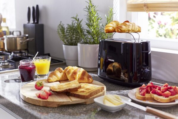 Ontbijt met croissants, toast en sinaasappelsap in keuken.