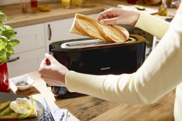 Persoon stopt brood in broodrooster in keuken