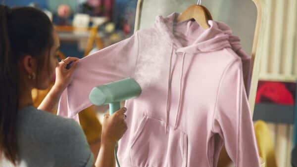 Roze hoodie gestoomd op hangertje.