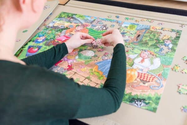 Persoon maakt kleurrijke legpuzzel op tafel.