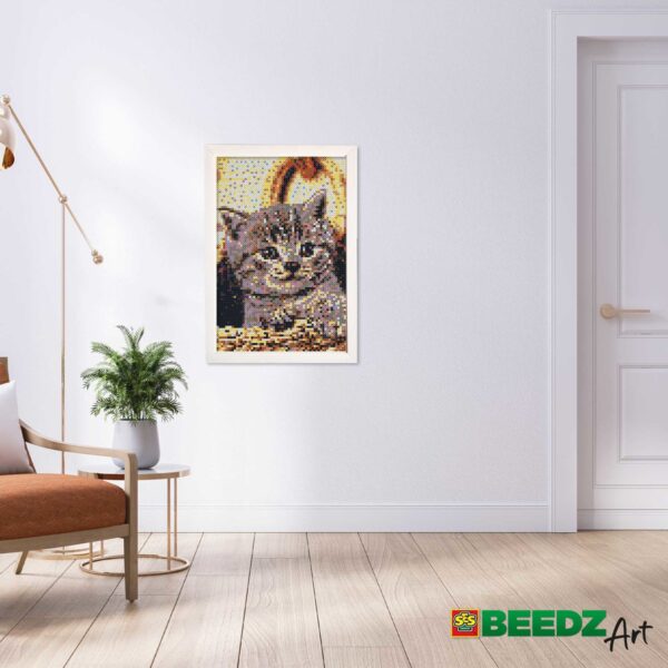 Ingelijste kattenkunst aan muur met plant en stoel.