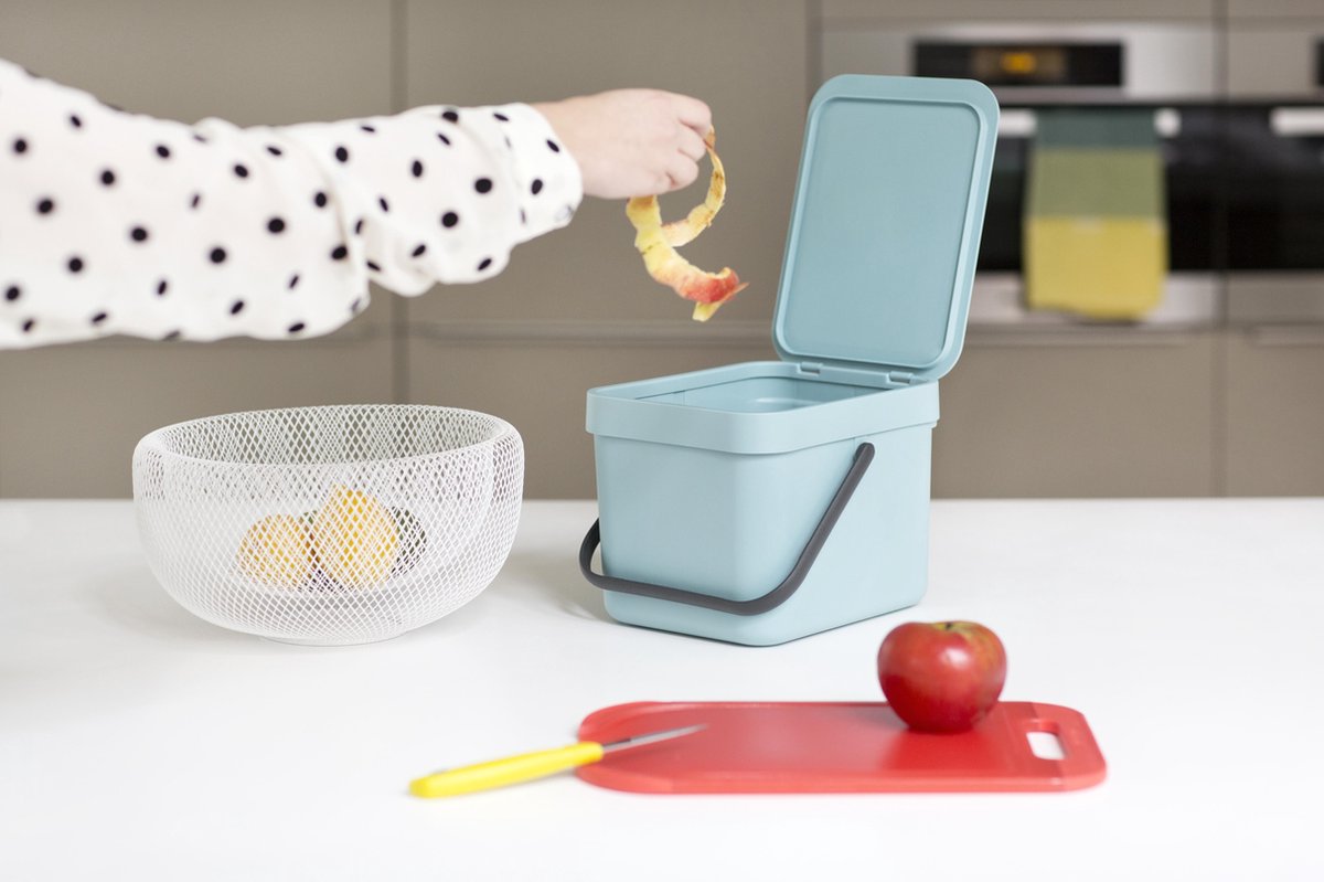 Keukenafval wordt in blauwe bak gegooid.