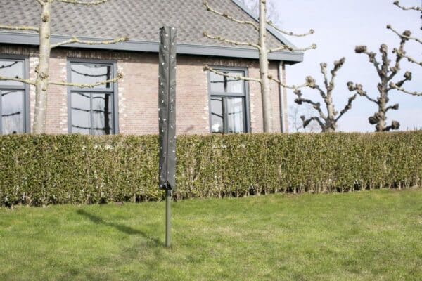 Parasol met hoes in tuin bij bakstenen huis.