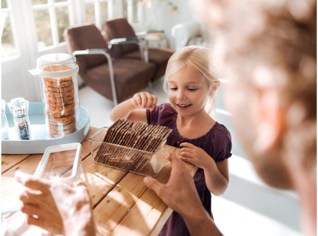 Kind pakt koekjes bij houten tafel