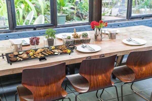 Eettafel met stoelen, eten en planten in serre