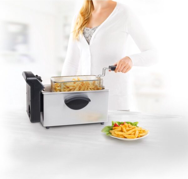 Vrouw gebruikt friteuse met mand vol frietjes.