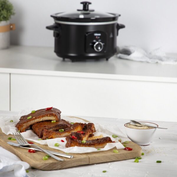 Slowcooker met spareribs op snijplank en sesamzaadjes.