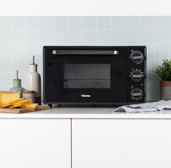 Zwarte oven op aanrecht met accessoires.