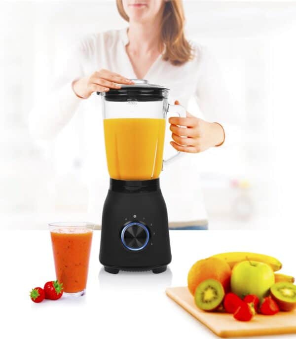 Vrouw maakt smoothie met blender en fruit.