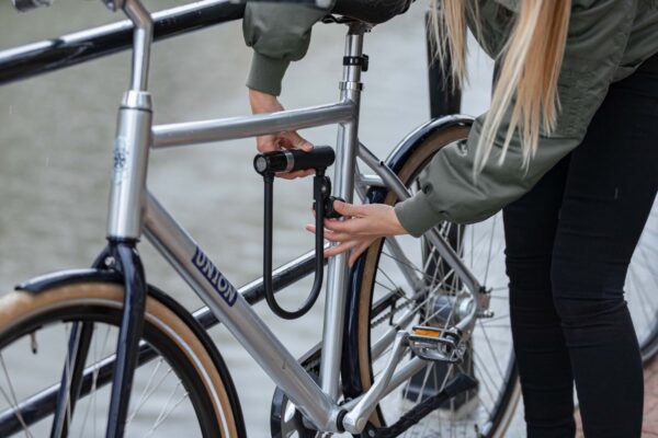 Vrouw beveiligt fiets met slot bij de gracht.