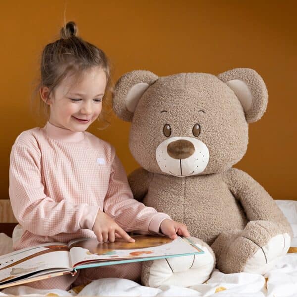 Kind leest boek naast teddybeer