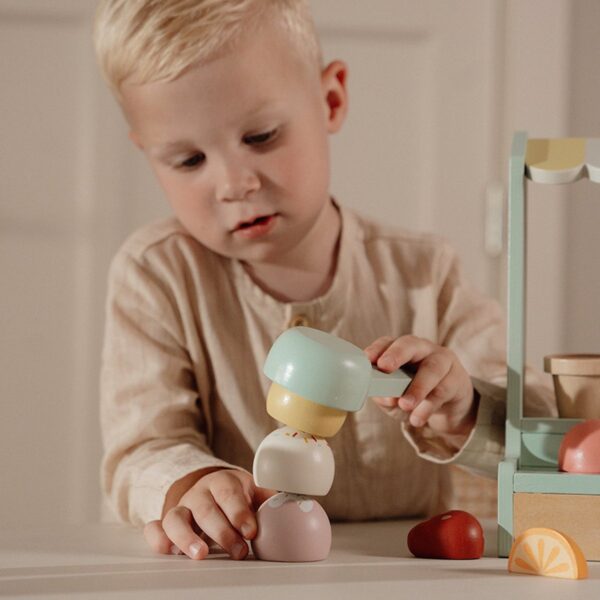 Kind speelt met houten speelgoedfiguren op tafel.