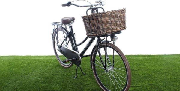 Zwarte fiets met rieten mand op groene grasmat