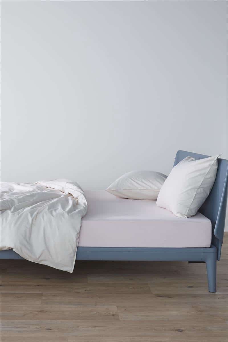 Moderne blauwe eenpersoonsbed met witte lakens.