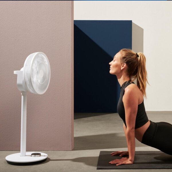 Vrouw doet yoga voor een ventilator binnenshuis.