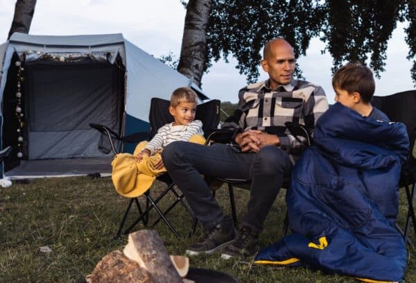 Familie kampeert bij tent in de avond.