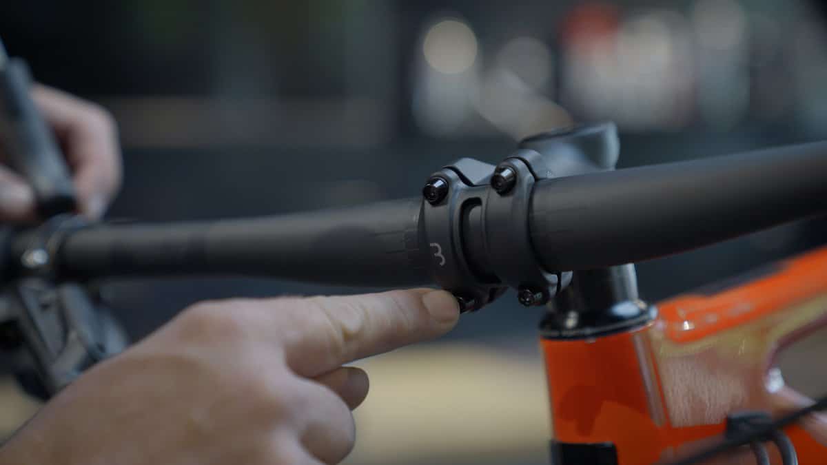 Finger points to the handlebar clamp on a mountain bike