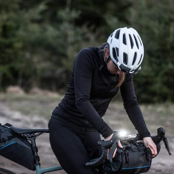 Fietser met helm controleert zadeltas in het bos.