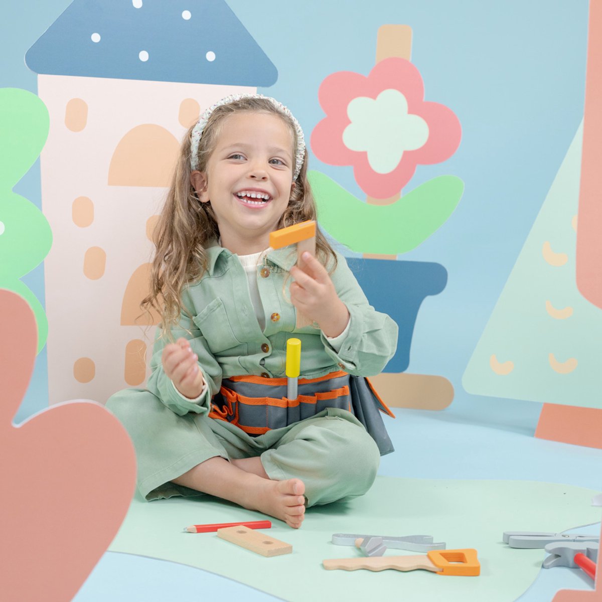 Lachend kind speelt met speelgoed in kleurrijke kamer.