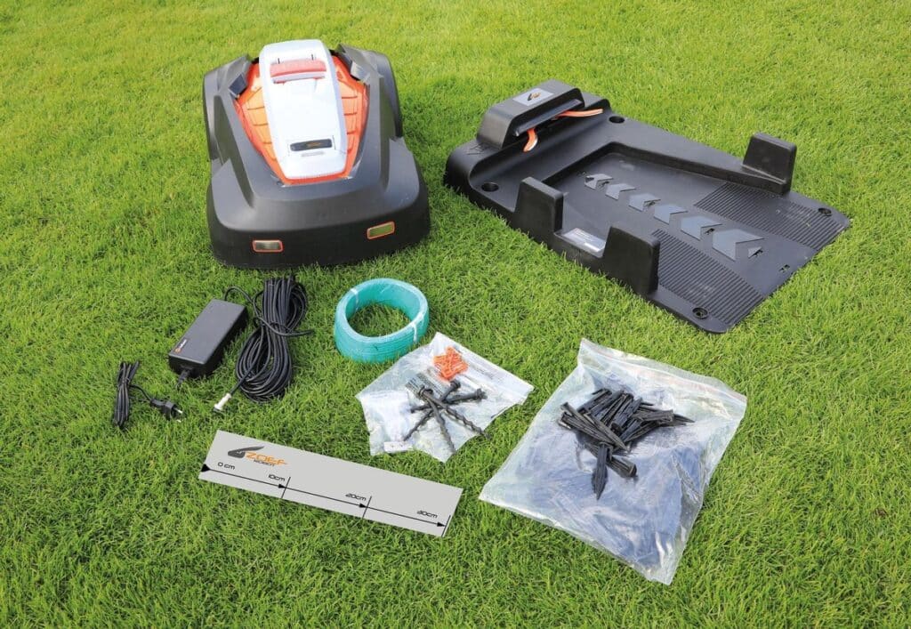 Robotmaaier met accessoires en laadstation op grasveld.